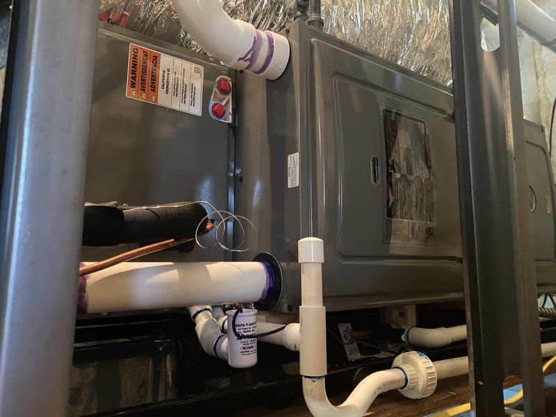 An installed indoor air handler with piping and safety switch