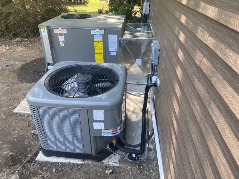 A newly installed clean outdoor condenser and package unit beside a home